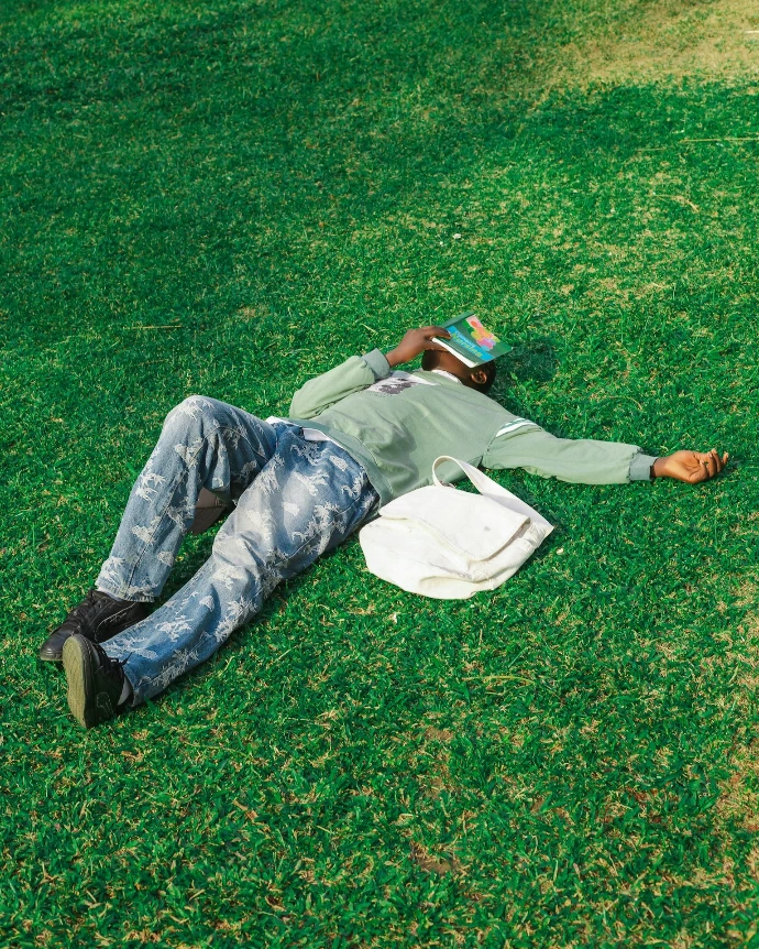 Man lying on grass reading a book.