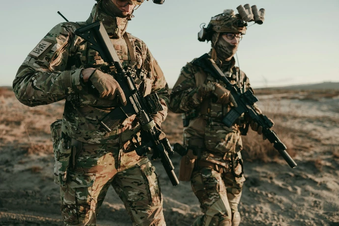 Soldiers walk through a desert landscape.